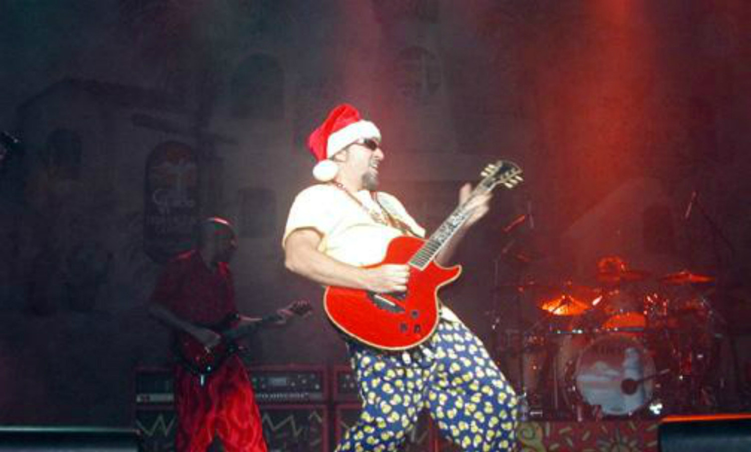 A man in a santa claus outfit playing a guitar.