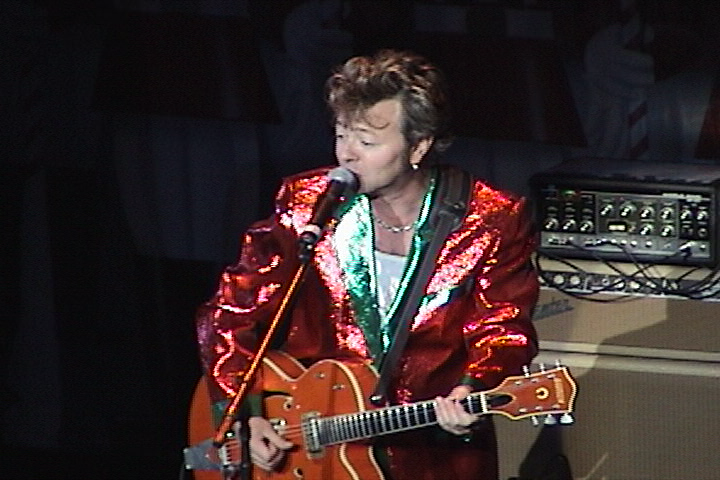 A man in a red suit singing into a microphone.