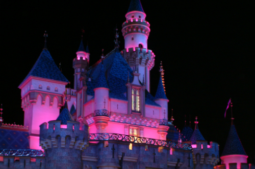 A castle lit up at night with pink lights.
