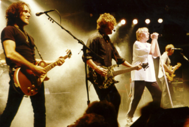 A group of men playing guitars on stage.