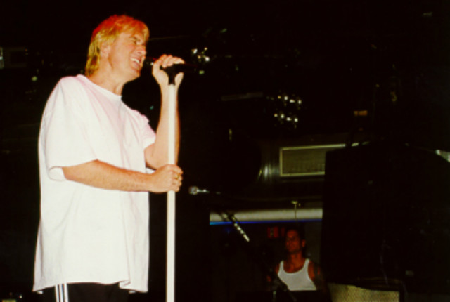 A man in a white shirt is holding a microphone.