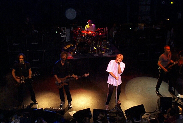 A group of people standing on stage at a concert.