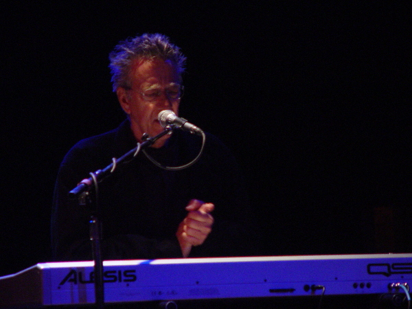 A man playing a keyboard in front of a microphone.