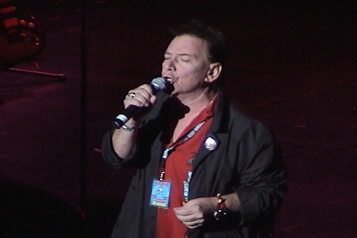 A man in a red shirt is holding a microphone.