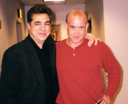 Two men standing next to each other in a hallway.