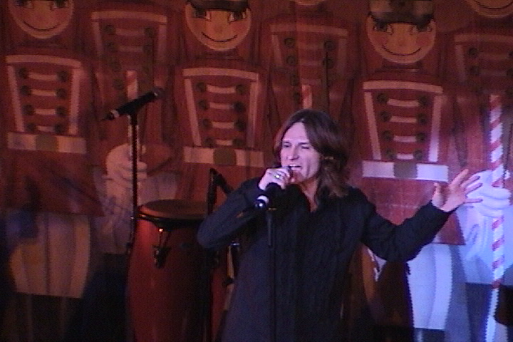 A woman singing into a microphone in front of a group of soldiers.