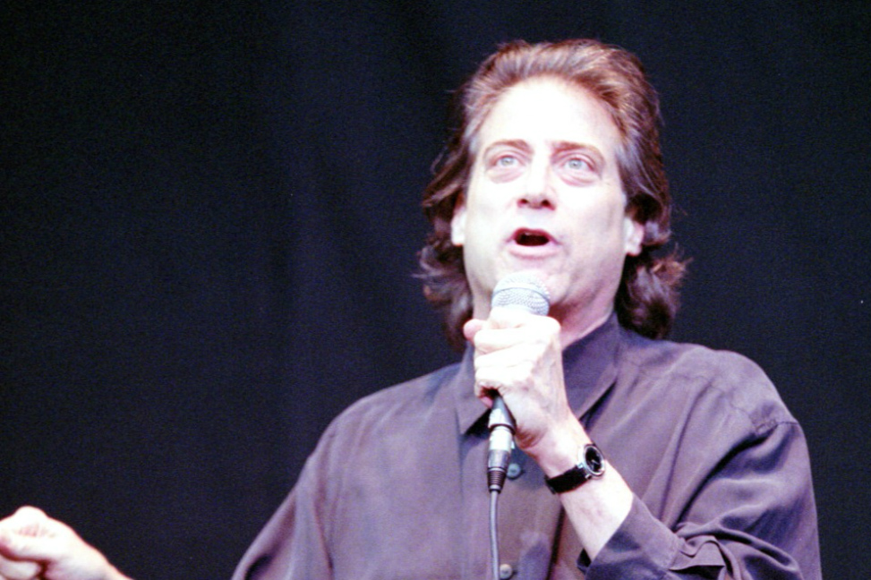 A man in a black shirt is holding a microphone.