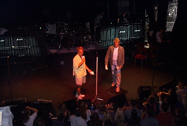 Two men standing on stage in front of a crowd.