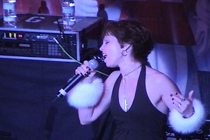 A woman in a black dress singing into a microphone.