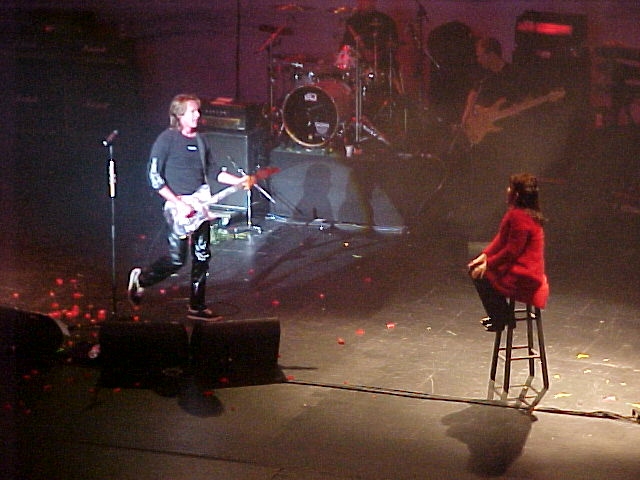 Two people sitting on stools on a stage.