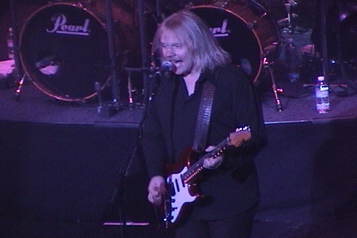A man playing guitar in front of a microphone.