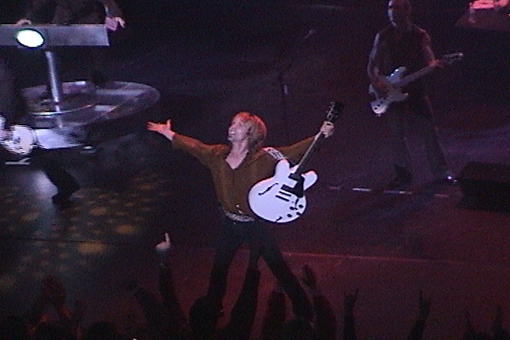 A man holding a guitar in front of a crowd.