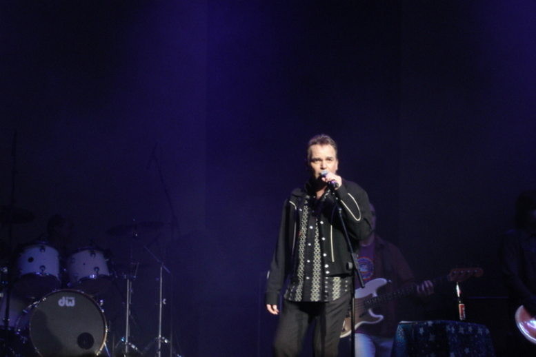 A man on stage singing into a microphone.