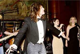 A man in a tuxedo is singing into a microphone.
