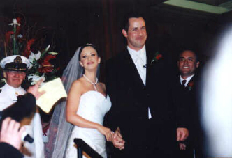 A bride and groom are standing together in front of the wedding party.