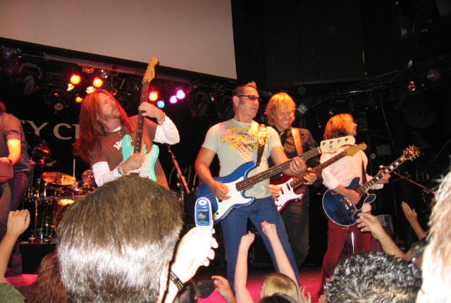 A group of people playing guitar on stage.