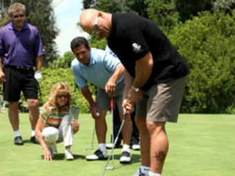 A group of people playing golf on the green.