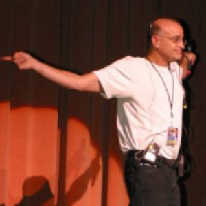 A man in white shirt and black pants on stage.