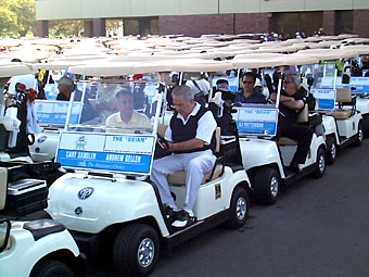 A group of people in golf carts on the street.