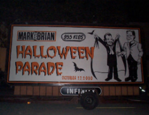 A large sign advertising halloween parade on the side of a building.