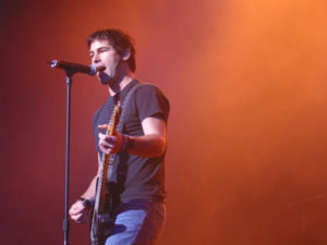 A man holding a microphone and singing on stage.