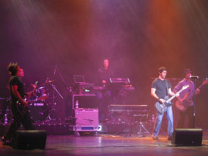 A man in black shirt playing guitar on stage.