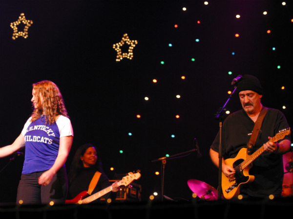 A band performing on stage with lights in the background.