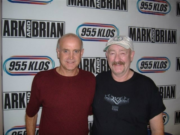 Two men standing in front of a wall with the words " mark brian ".