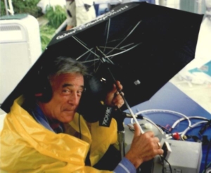A man in yellow jacket holding an umbrella.