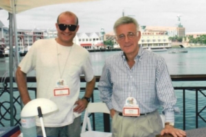 Two men standing next to each other in front of a table.