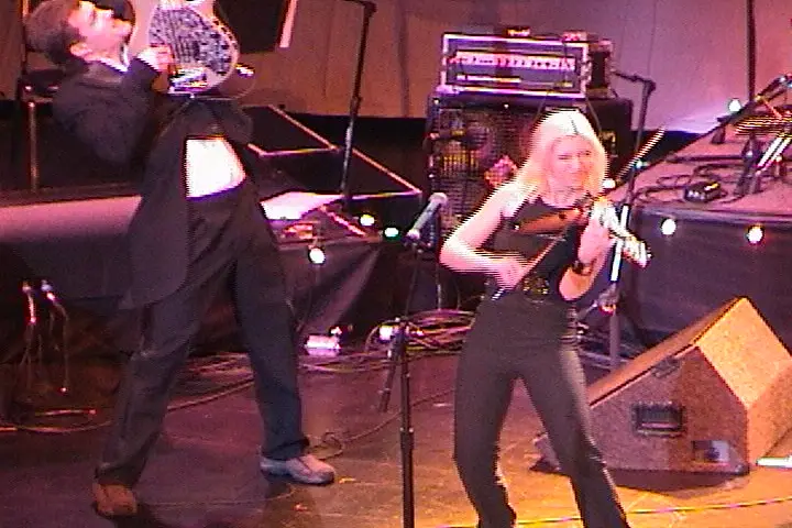 A woman in a tuxedo and a man in a tuxedo on stage.