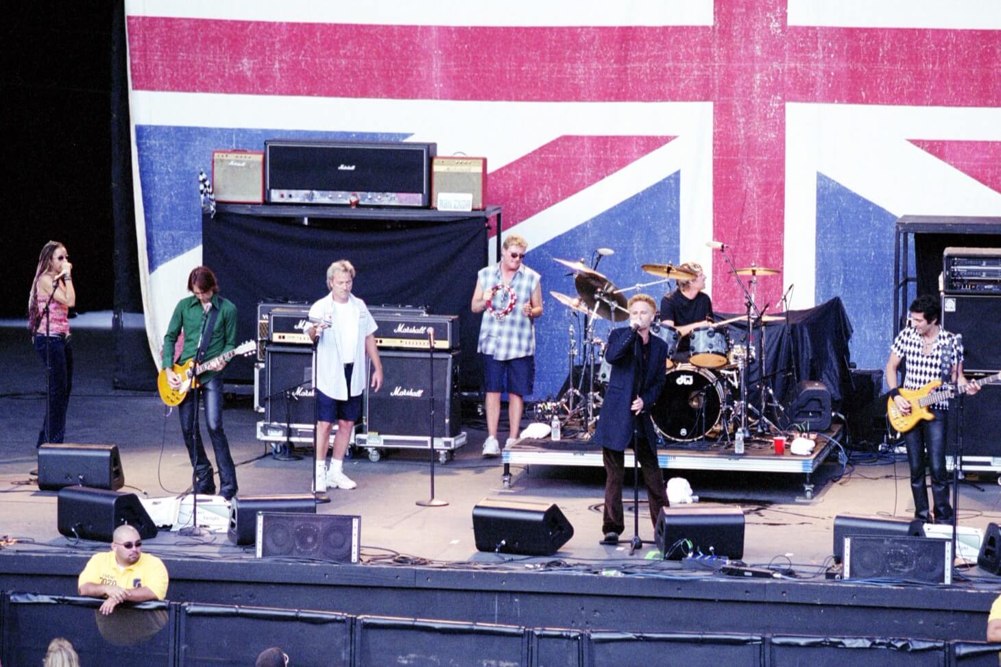 A group of people on stage with a british flag behind them.